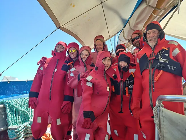 Students, voyagers, and crew of C-285 happily don immersion suits during today's ship safety orientation.