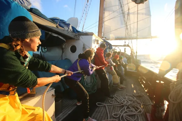 Many hands hauling on the main sail halyard