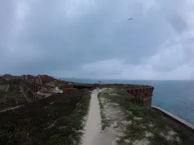 The view atop Fort Jefferson, with a Frigate flying over Alex and the Corwith Cramer in the background