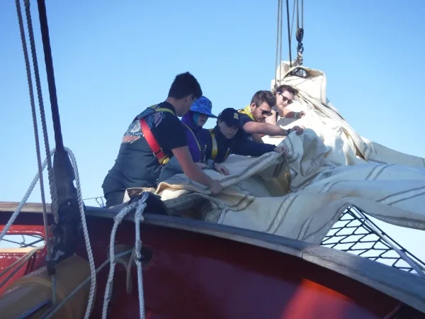 Furling the jib in-between conducting oceanography and looking at the megafauna that appears on the Hauraki Gulf, Aotearoa New Zealand. That's the author, Marija, with the Rochester hat in the middle.