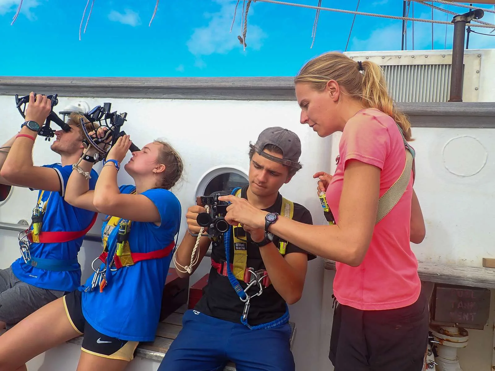 Carolyn showing Harrison, Audrey and Sam how to use sextants to shoot the sun